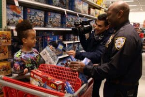 A man in uniform handing toys to a child.