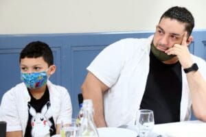 A man and boy wearing masks at a table.