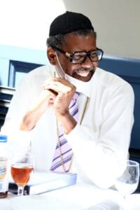 A man sitting at a table with his hand on the phone.