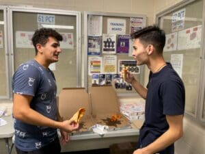 Two young men are eating a hot dog.