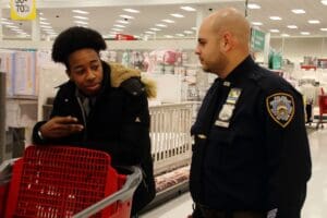 A man and woman talking in front of a shopping cart.