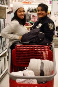 A woman and man in uniform are sitting on the shopping cart.