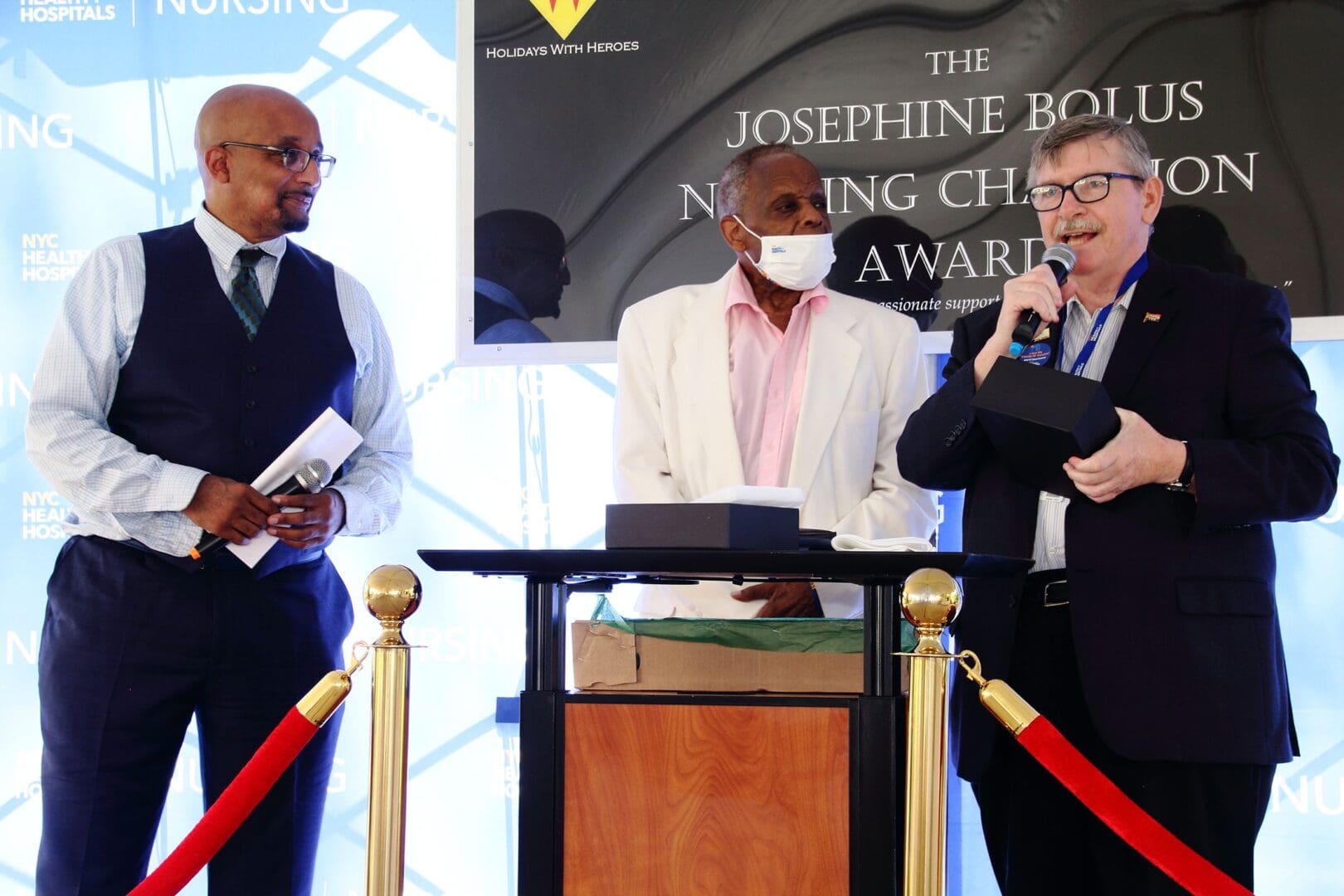 Three men standing at a podium with microphones.