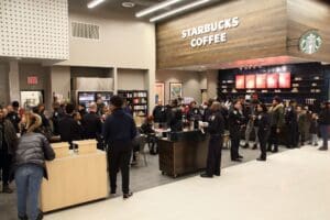 A crowd of people standing around a starbucks coffee shop.