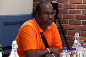 A man in an orange shirt sitting at a table.