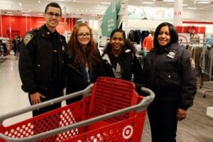 A group of people standing around a red shopping cart.