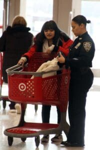 A woman pushing a shopping cart with a man standing next to it.