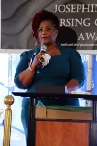 A woman is speaking at an event with a microphone.