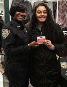 Two women in police uniforms holding a box of candy.