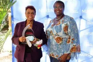 Two women standing next to each other holding a basket.