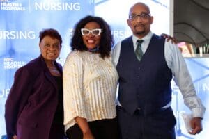 Three people posing for a picture in front of a blue wall.