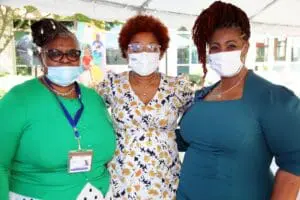 Three women wearing masks and standing next to each other.