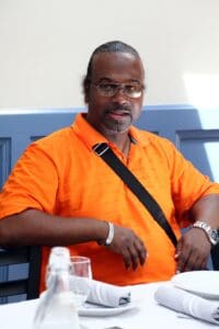 A man in an orange shirt and glasses.