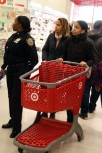 A group of people standing around a red shopping cart.