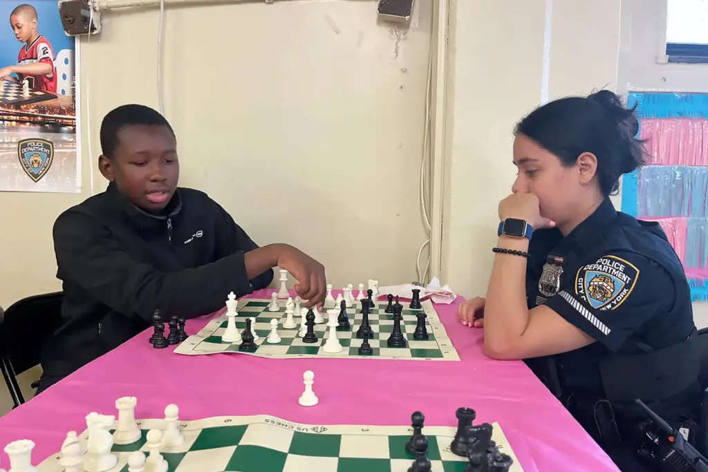 Two people sitting at a table playing chess.